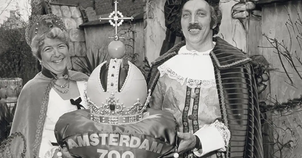 Two Dutch people hold a large decorative crown, celebrating Amsterdam's 700th anniversary Two Dutch people hold a large decorative crown, celebrating Amsterdam's 700th anniversary