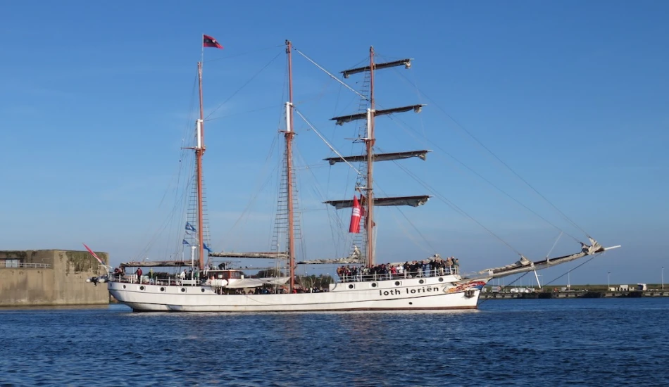 The tall ship Loth Loriën sailing on calm waters with passengers on deck.