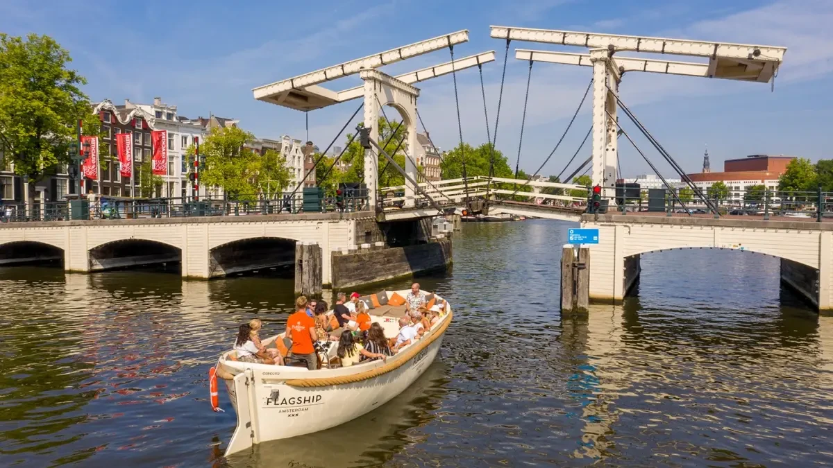 A boat carrying passengers sailing in a canal.