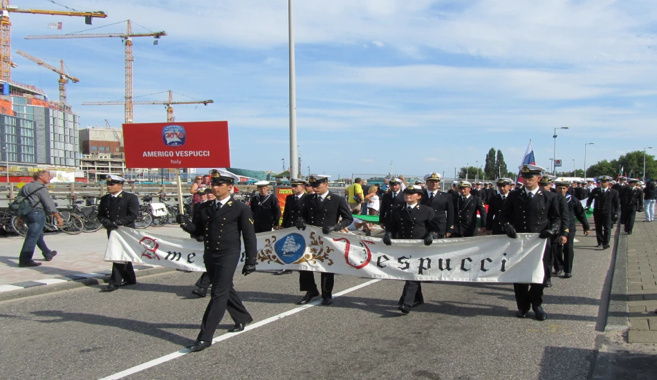 Sailors in black uniforms march proudly with a banner reading "Amerigo Vespucci, Italy".