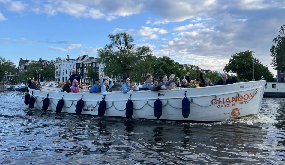 A group of people on an open boat in a canal, enjoying drinks.