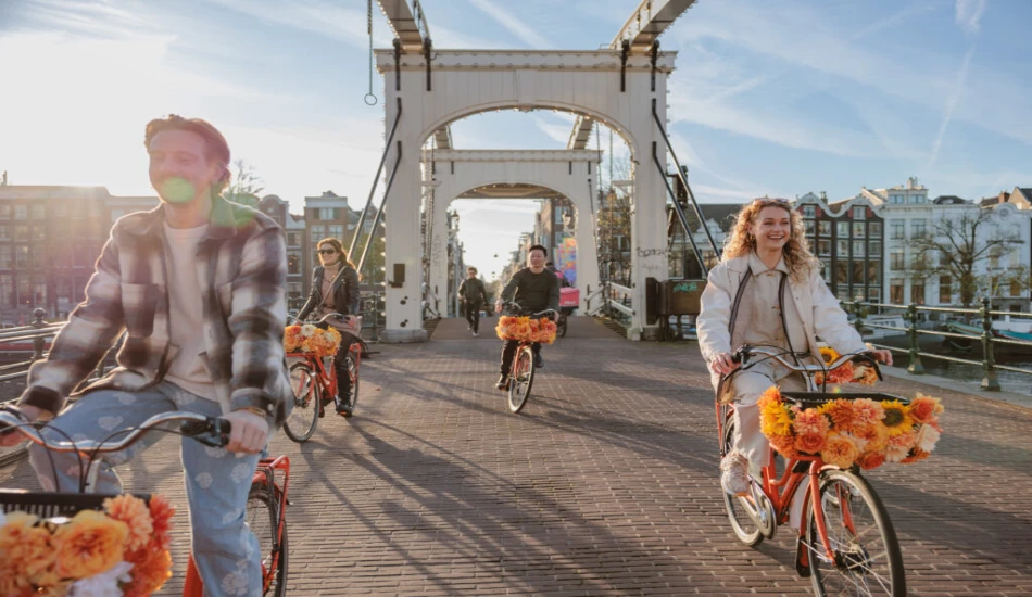 Group of happy cyclists crossing a canal bridge in Amsterdam.