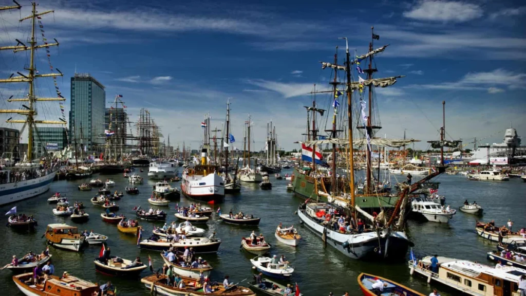 Small boats surrounding tall ships at Sail Amsterdam event
