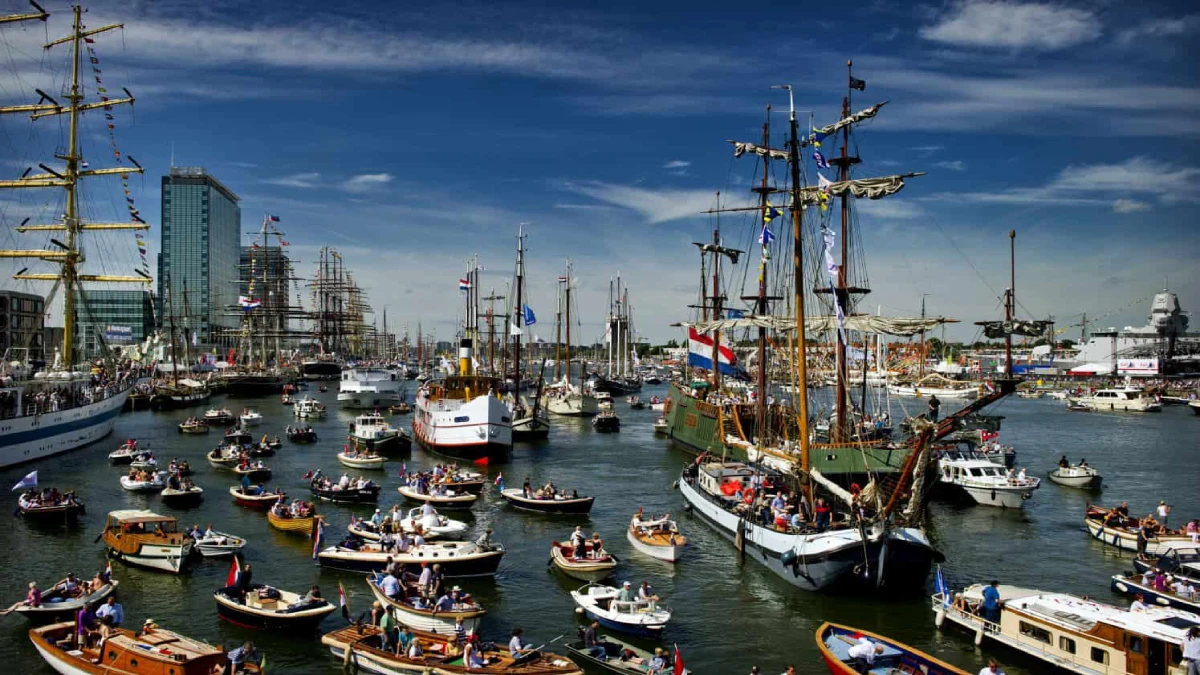 Small boats surrounding tall ships at Sail Amsterdam event
