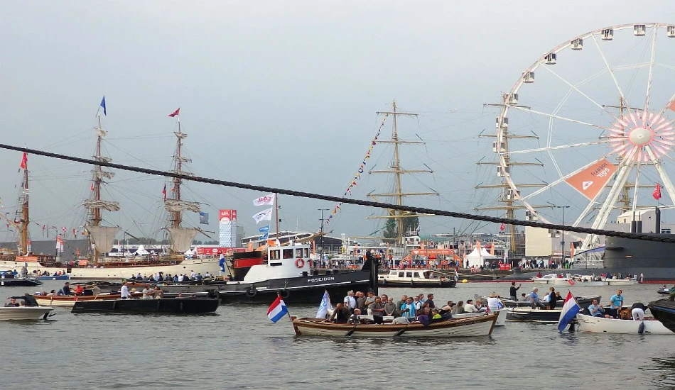 Busy harbor scene during Sail Amsterdam with historic ships and waterfront attractions.